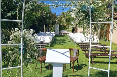 Salle de réception décorée avec des tables dressées, nappes blanches, serviettes pliées et arrangements floraux.