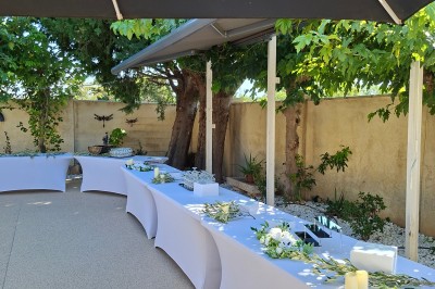 Salle de réception décorée avec des tables dressées, nappes blanches, serviettes pliées et arrangements floraux.