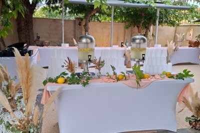 Salle de réception décorée avec des tables dressées, nappes blanches, serviettes pliées et arrangements floraux.
