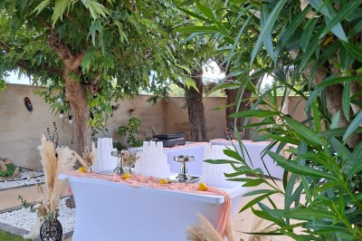 Salle de réception décorée avec des tables dressées, nappes blanches, serviettes pliées et arrangements floraux.