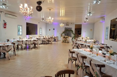 Salle de réception décorée avec des tables dressées, nappes blanches, serviettes pliées et arrangements floraux.