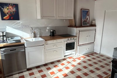 Cuisine rustique avec murs en pierre, poutres apparentes, meubles en bois et appareils électroménagers modernes.