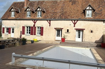 Cuisine rustique avec murs en pierre, poutres apparentes, meubles en bois et appareils électroménagers modernes.