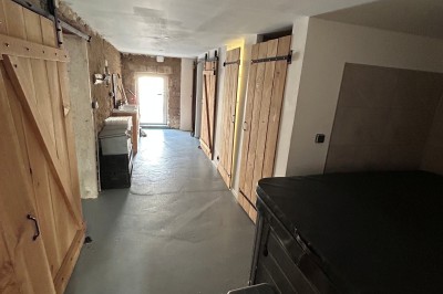 Cuisine rustique avec murs en pierre, poutres apparentes, meubles en bois et appareils électroménagers modernes.