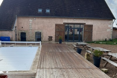 Cuisine rustique avec murs en pierre, poutres apparentes, meubles en bois et appareils électroménagers modernes.