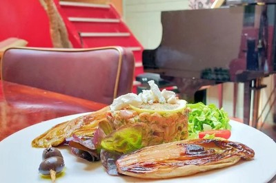 Miniature Location salle Montreuil (Seine-Saint-Denis) - Gabriella #9 Assiette garnie de légumes grillés, salade et os à moelle, posée sur une table en bois près d'un piano noir.