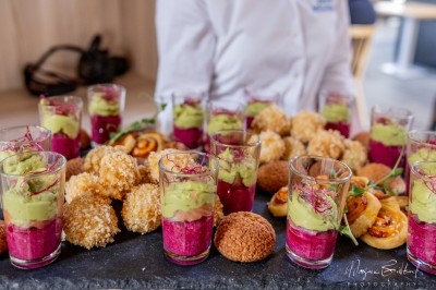 Plateau de bouchées apéritives variées comprenant verrines, choux garnis et feuilletés, disposés sur une table.
