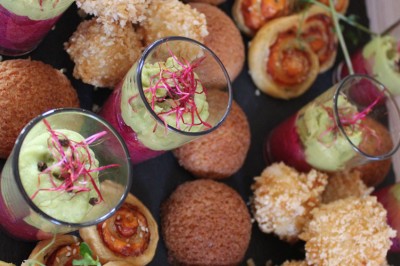 Plateau de bouchées apéritives variées comprenant verrines, choux garnis et feuilletés, disposés sur une table.