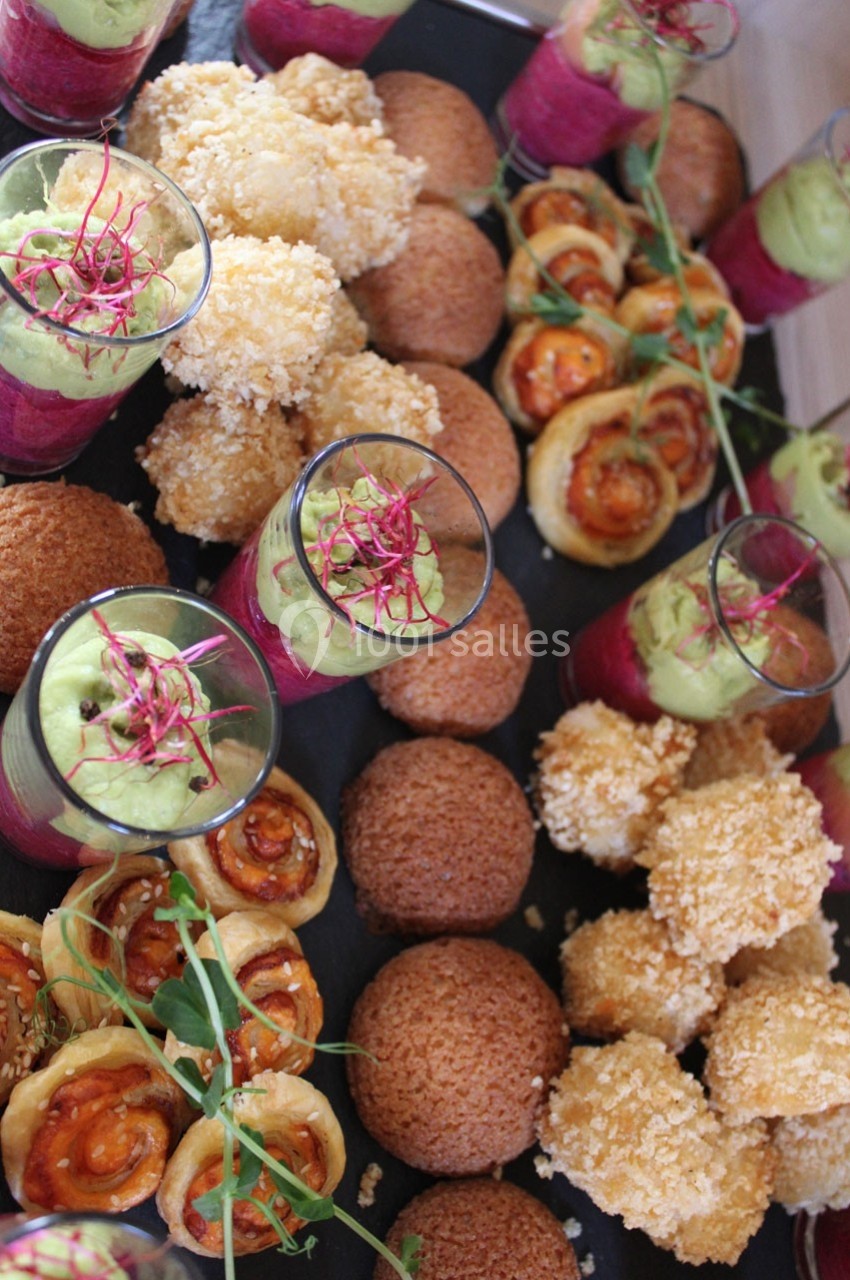 Plateau de bouchées apéritives variées comprenant verrines, choux garnis et feuilletés, disposés sur une table.