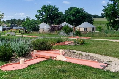 Cuisine ouverte avec table ronde, chaises blanches, canapé, télévision et fenêtre laissant entrer la lumière naturelle.