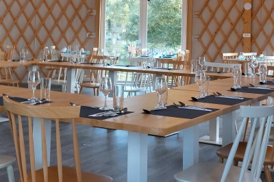 Cuisine ouverte avec table ronde, chaises blanches, canapé, télévision et fenêtre laissant entrer la lumière naturelle.