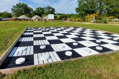Cuisine ouverte avec table ronde, chaises blanches, canapé, télévision et fenêtre laissant entrer la lumière naturelle.