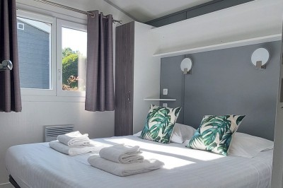 Cuisine ouverte avec table ronde, chaises blanches, canapé, télévision et fenêtre laissant entrer la lumière naturelle.