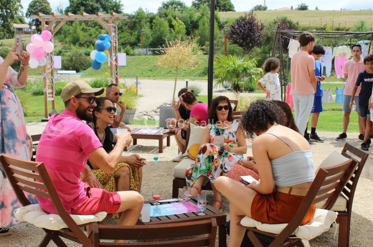 Groupe de personnes assises en extérieur, discutant et partageant un moment convivial dans un cadre estival.