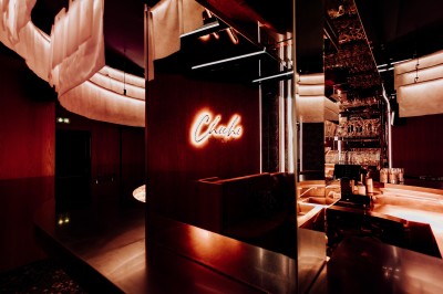 Intérieur d'un bar moderne avec comptoir incurvé, éclairage suspendu et banquettes rouges.