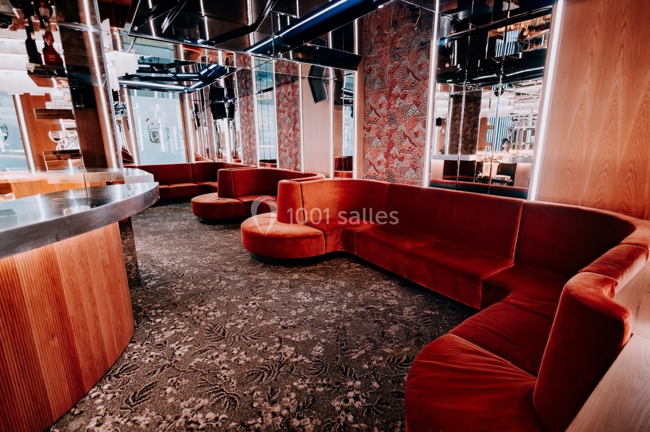 Banquettes en velours rouge disposées en arc de cercle dans un intérieur moderne avec murs en bois et miroirs.