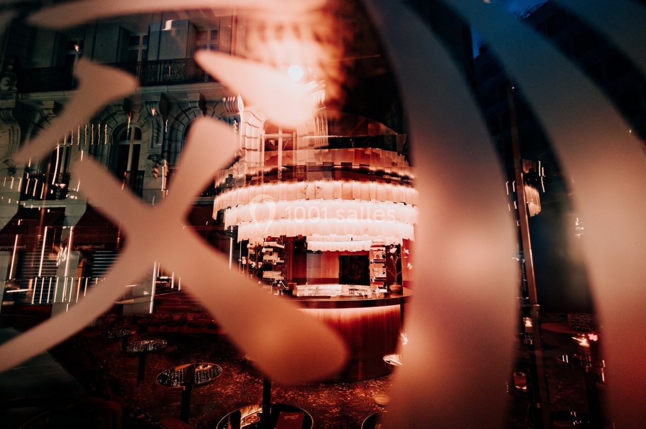 Reflet d'un intérieur de bar avec des lumières tamisées et des éléments décoratifs visibles à travers une vitre.