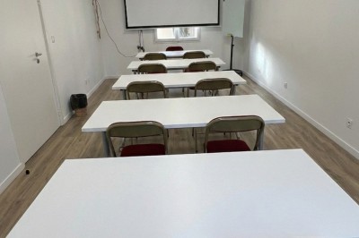 Miniature Salle de Sycomore Des personnes debout dans une salle décorée, tenant des verres, devant des tables dressées pour une fête.