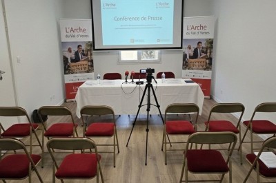 Miniature Salle de Sycomore Des personnes debout dans une salle décorée, tenant des verres, devant des tables dressées pour une fête.