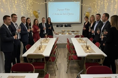 Miniature Salle de Sycomore Des personnes debout dans une salle décorée, tenant des verres, devant des tables dressées pour une fête.