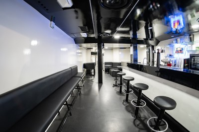 Salle voûtée en pierre avec éclairage LED coloré, mobilier minimaliste et comptoir de bar au fond.