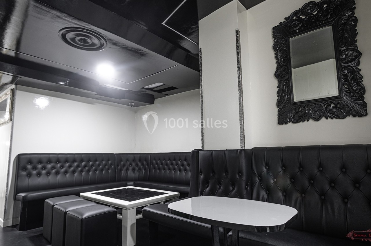 Banquettes en cuir noir entourant des tables blanches dans un espace intérieur moderne et épuré.