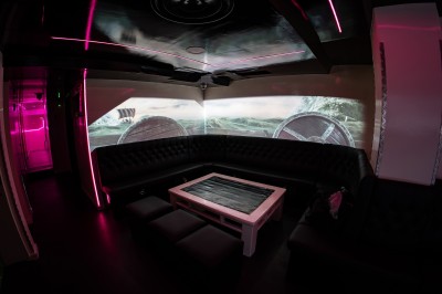 Salle voûtée en pierre avec éclairage LED coloré, mobilier minimaliste et comptoir de bar au fond.