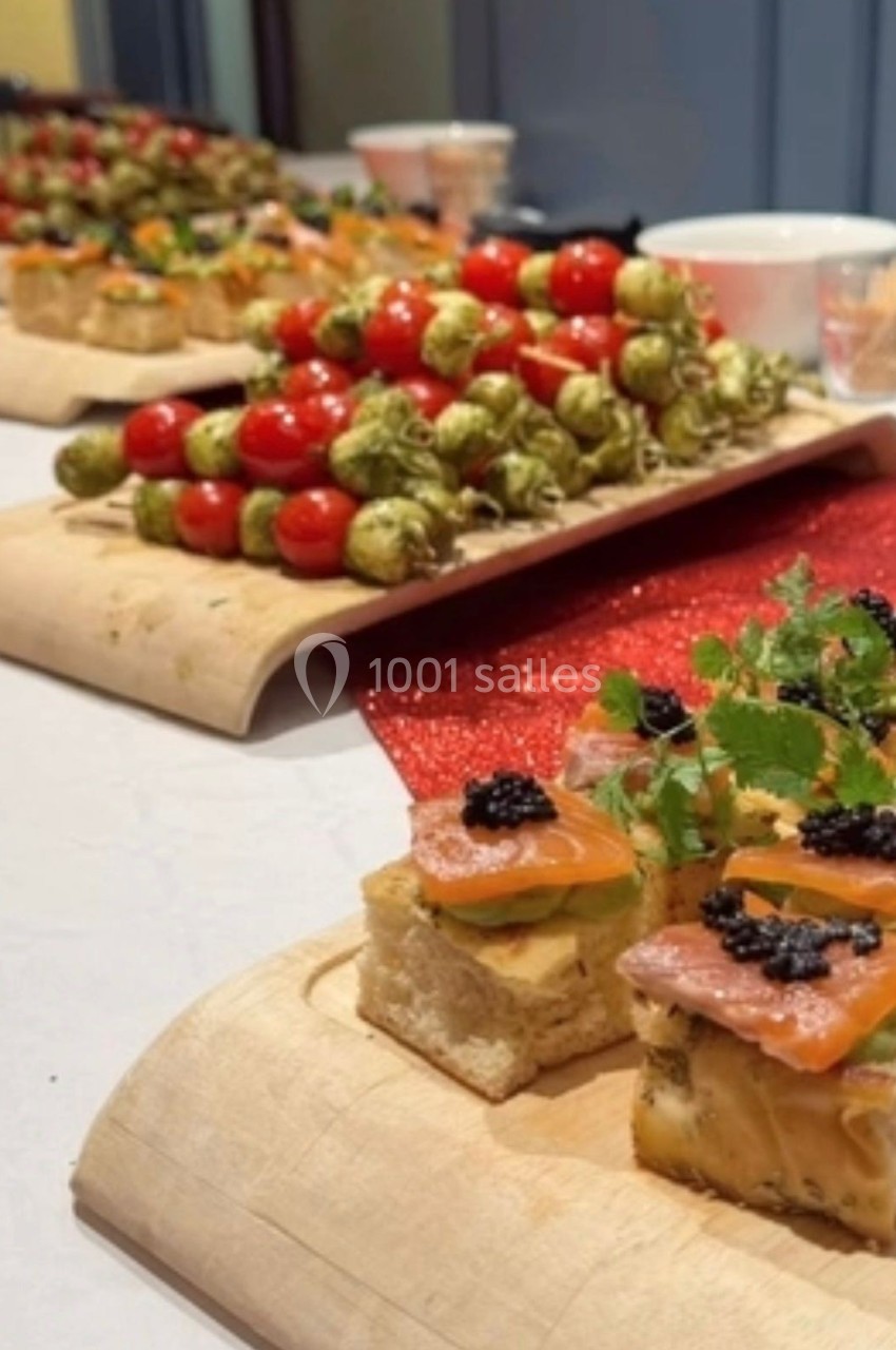 Plateaux de canapés variés avec brochettes de tomates cerises et amuse-bouches au saumon et caviar sur une table.