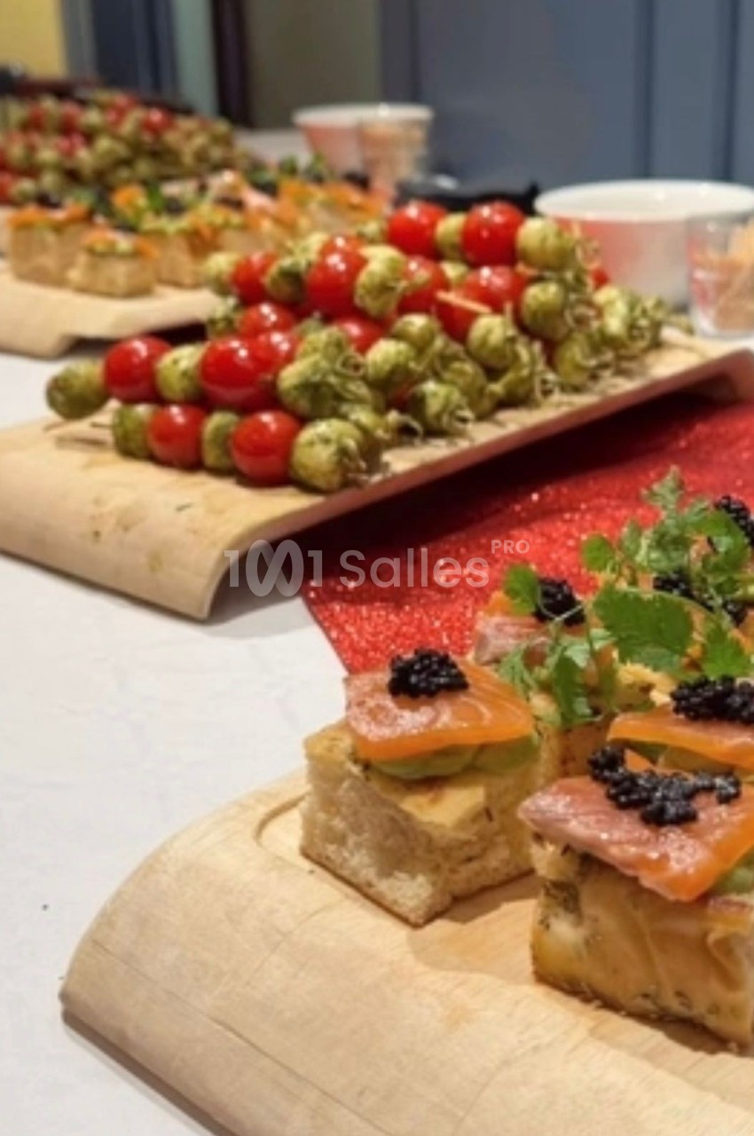 Plateaux de canapés variés avec brochettes de tomates cerises et amuse-bouches au saumon et caviar sur une table.