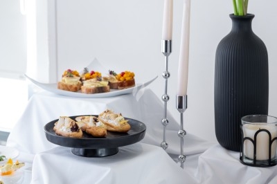 Table dressée avec des amuse-bouches variés, des bougies blanches et un vase noir contenant des callas.