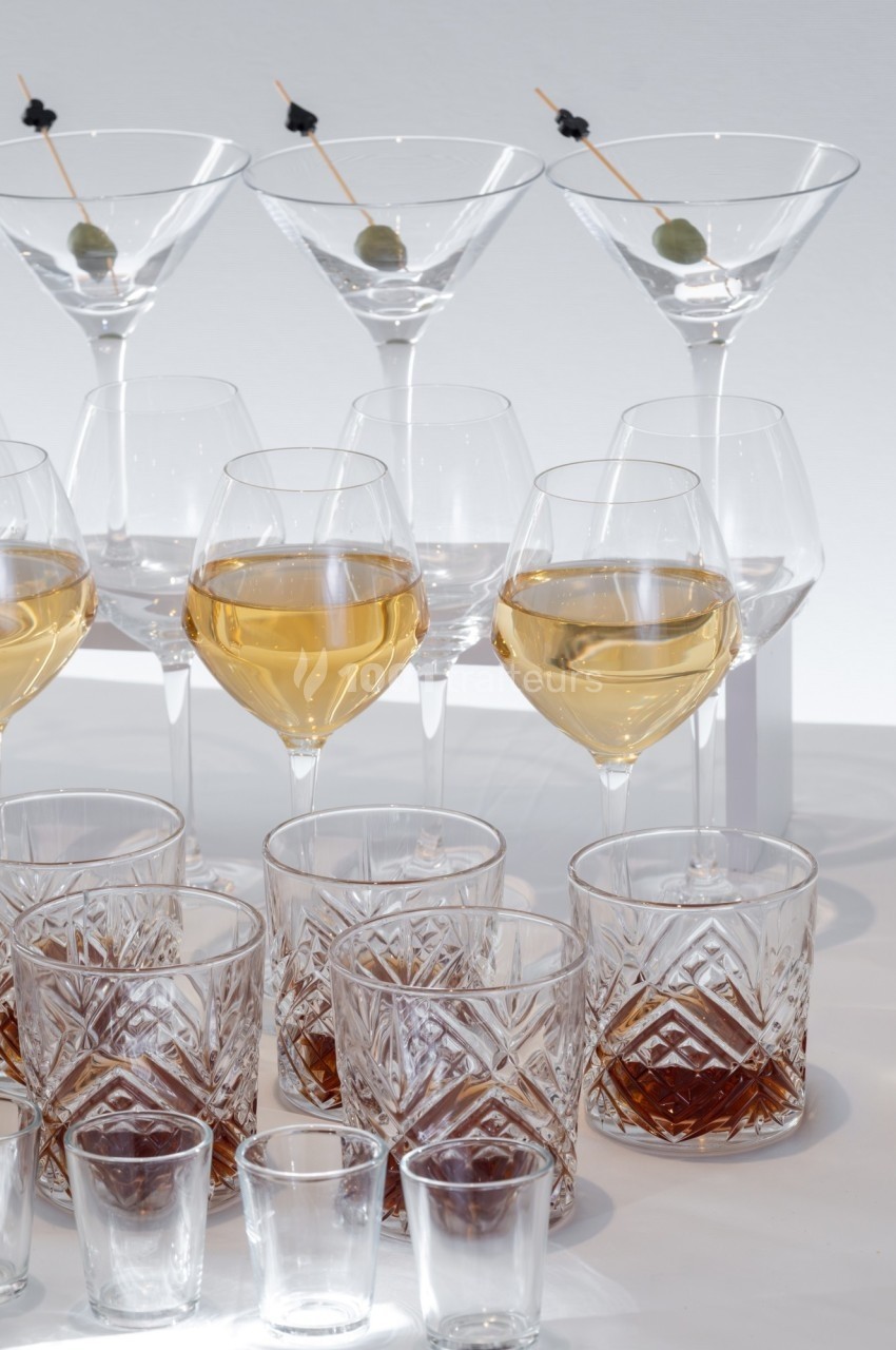 Verres variés contenant des boissons alcoolisées et non alcoolisées, disposés sur une surface blanche.