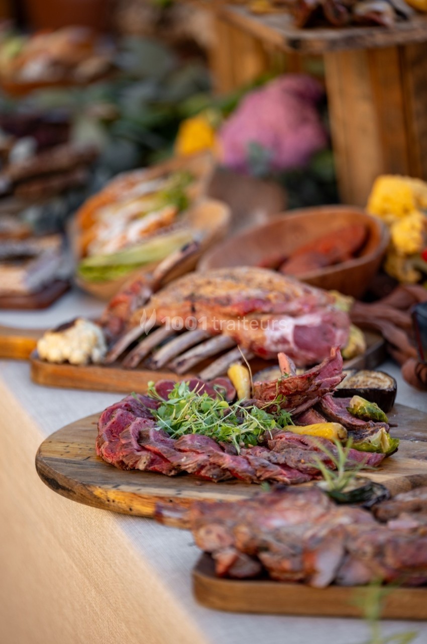 Plateaux de viandes grillées et tranchées, garnis d'herbes fraîches, présentés sur des planches en bois.