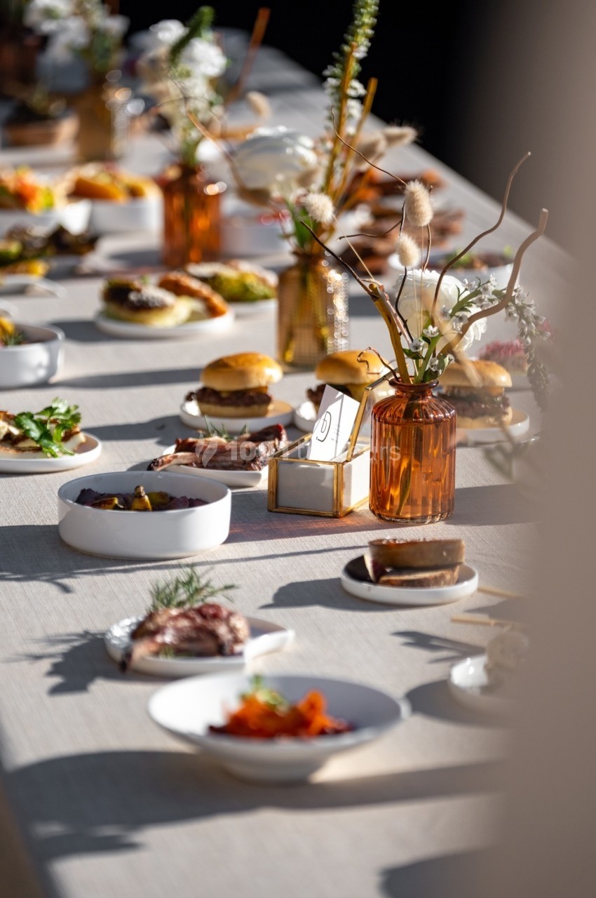 Table dressée avec divers plats, desserts et décorations florales dans des tons naturels et lumineux.