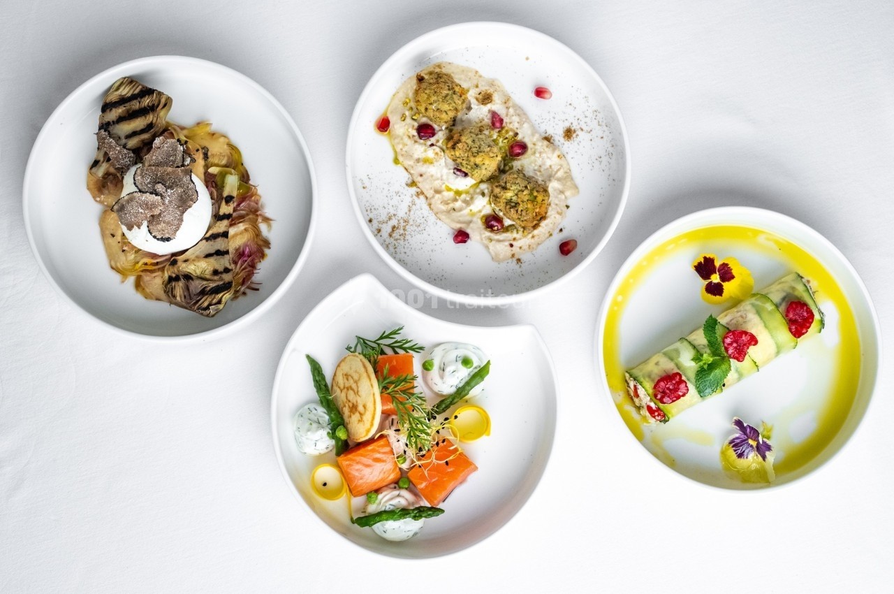 Quatre assiettes gastronomiques variées avec des présentations soignées et des ingrédients colorés.