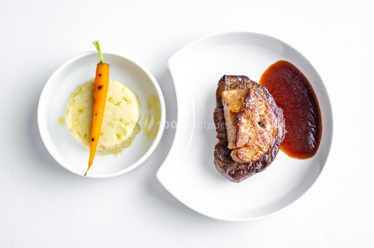 Assiette contenant un morceau de viande avec sauce, purée de pommes de terre et une carotte entière en garniture.