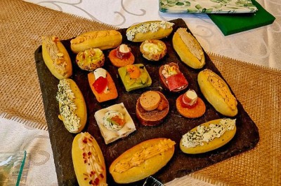 Table dressée avec une assiette blanche, une serviette rose ornée d'une feuille argentée, et des couverts cuivrés.