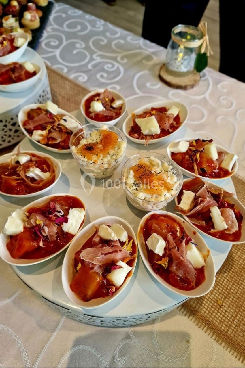 Plateau de verrines et coupelles garnies de préparations salées avec fromage, jambon et herbes, présenté sur une nappe beige.