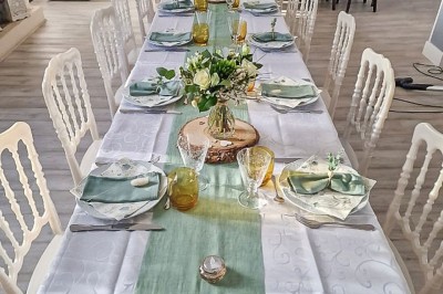 Table dressée avec une assiette blanche, une serviette rose ornée d'une feuille argentée, et des couverts cuivrés.
