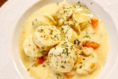 Table dressée avec une assiette blanche, une serviette rose ornée d'une feuille argentée, et des couverts cuivrés.