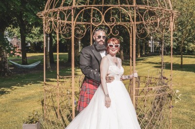 Table dressée avec une assiette blanche, une serviette rose ornée d'une feuille argentée, et des couverts cuivrés.