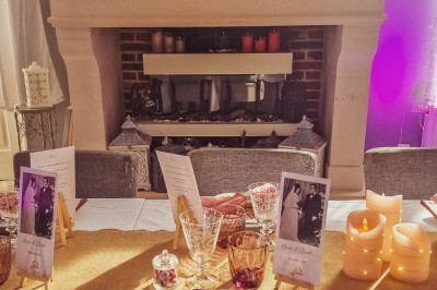 Table dressée avec une assiette blanche, une serviette rose ornée d'une feuille argentée, et des couverts cuivrés.