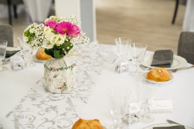 Table dressée avec une assiette blanche, une serviette rose ornée d'une feuille argentée, et des couverts cuivrés.