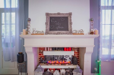 Table dressée avec une assiette blanche, une serviette rose ornée d'une feuille argentée, et des couverts cuivrés.