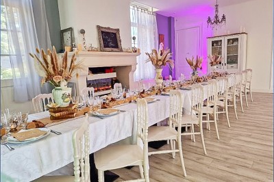 Table dressée avec une assiette blanche, une serviette rose ornée d'une feuille argentée, et des couverts cuivrés.