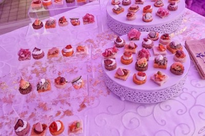 Table dressée avec une assiette blanche, une serviette rose ornée d'une feuille argentée, et des couverts cuivrés.