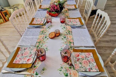 Table dressée avec une assiette blanche, une serviette rose ornée d'une feuille argentée, et des couverts cuivrés.