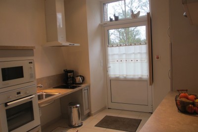 Miniature Location salle Montilliers (Maine-et-Loire) - Le Parc de Tirpoil #21 Cuisine professionnelle avec carrelage blanc, plan de travail en inox, évier, cuisinière et hotte.