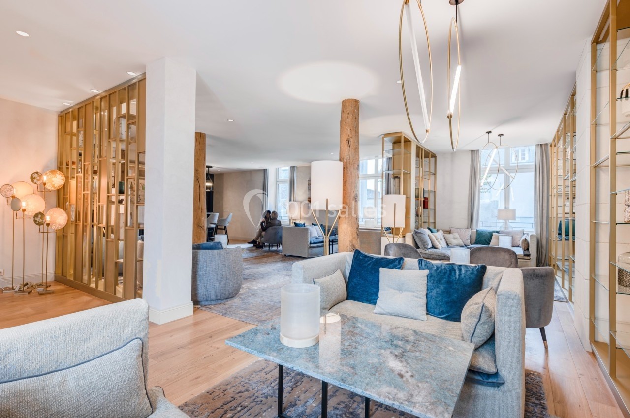 Salon moderne avec mobilier élégant, canapés bleus et gris, table basse en marbre, et éclairage design.