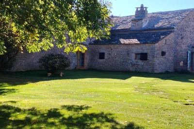 Chambre avec murs en pierre, lit double avec couverture blanche et cheminée ancienne en pierre.