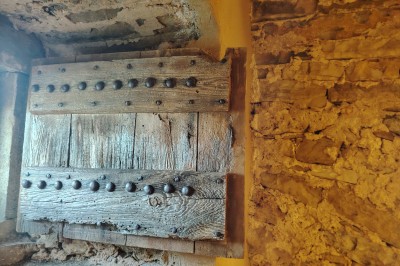 Maison en pierre traditionnelle avec toit en lauze, entourée d'une cour pavée et d'arbres dénudés en hiver.